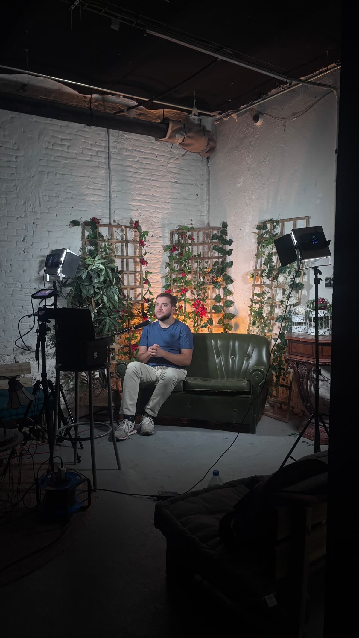 Invitado sentado en un sofá verde en el plató de Madrid centro, con luces de estudio y un fondo decorado con celosías y plantas